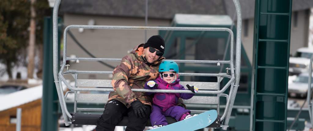 Dad and daughter on ski chairlift at Brighton