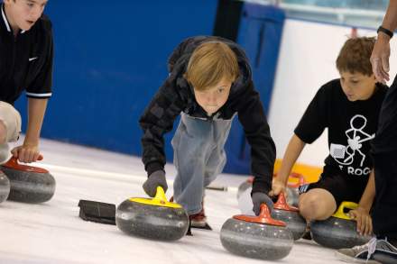 Child with an intense look of concentration sending a curling stone