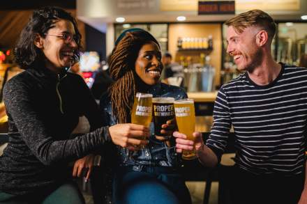 3 people, one man and two women, toasting with beer glasses