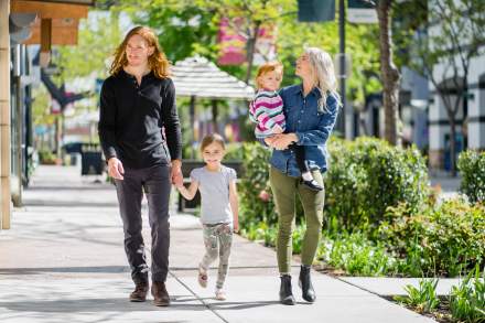 A man holding a child's hand and a woman holding another child walking down the street in Salt Lake